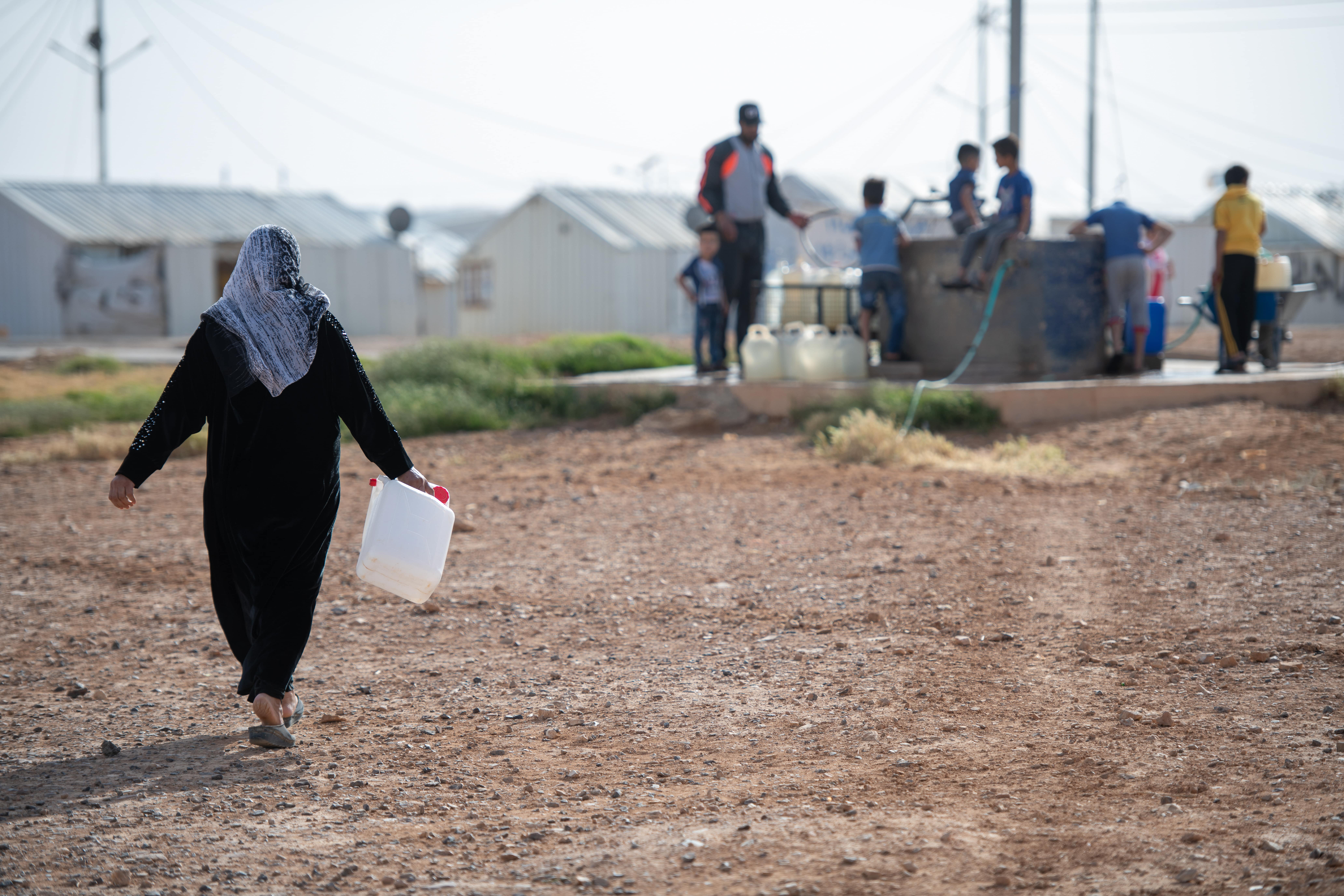 Syrian woman collects water in Jordan