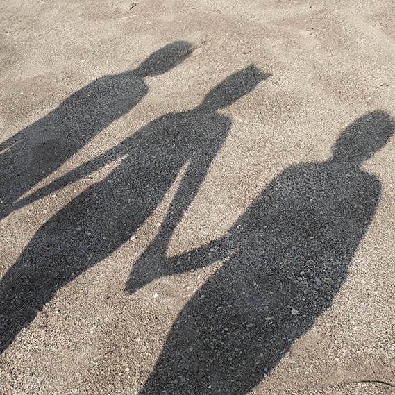 Three women's shadows cast on to the pavement, walking hand in hand 