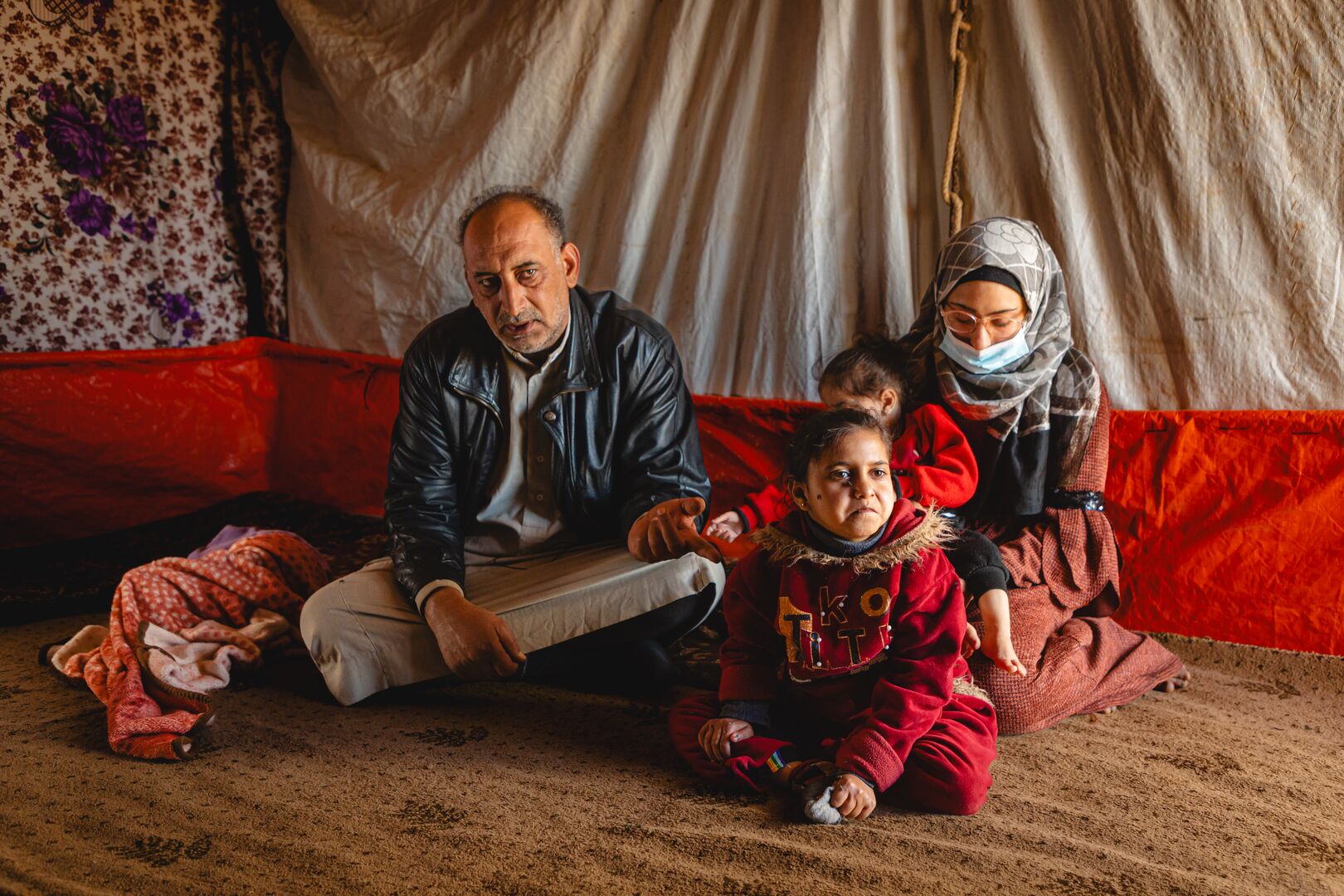 Syrian refugee, Khaled, sits with his children inside their tent in Amman, Jordan. 