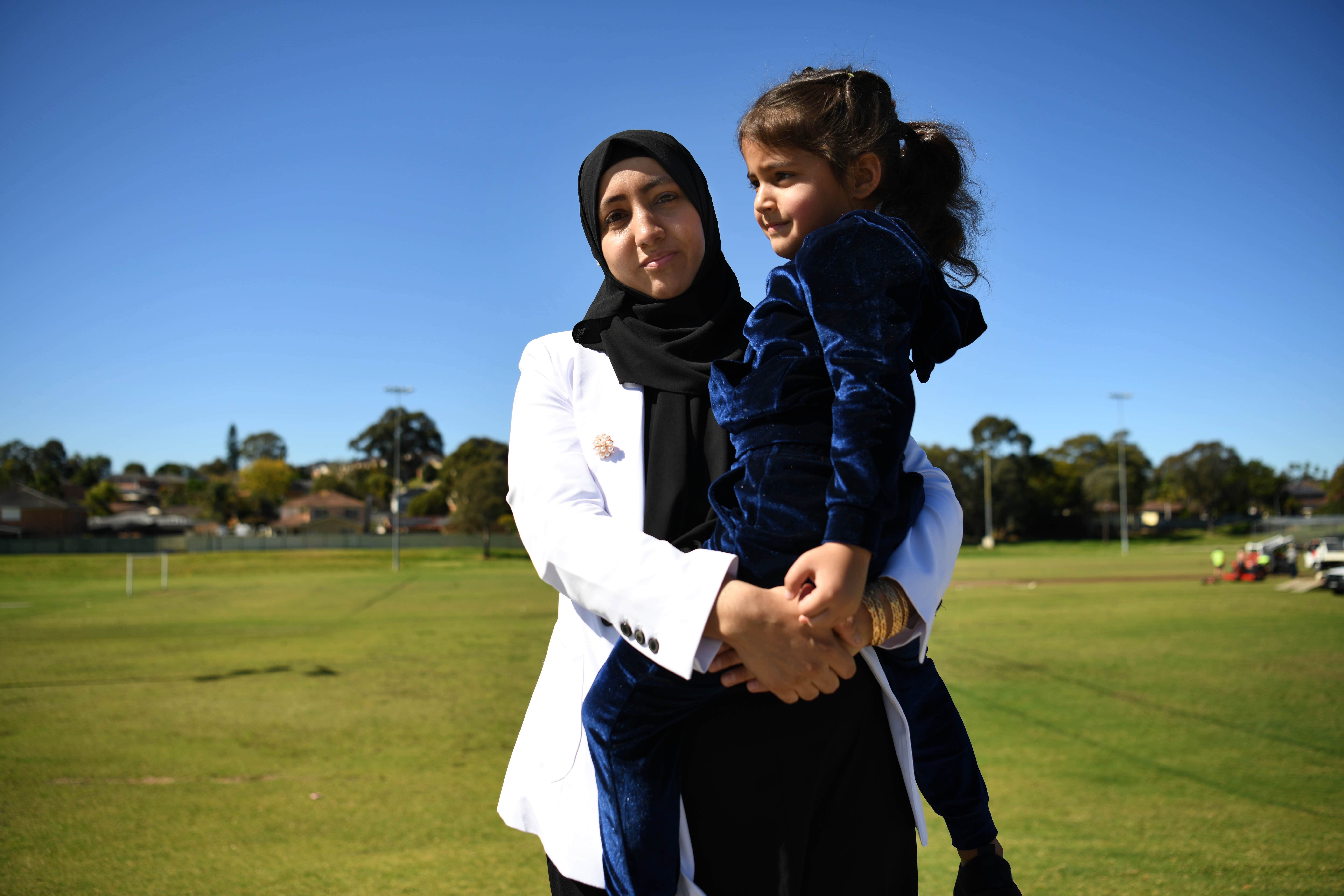 Judge Farah Altaf Atahee holds her four-year-old daughter, Aisha, in a sunny park in Sydney.