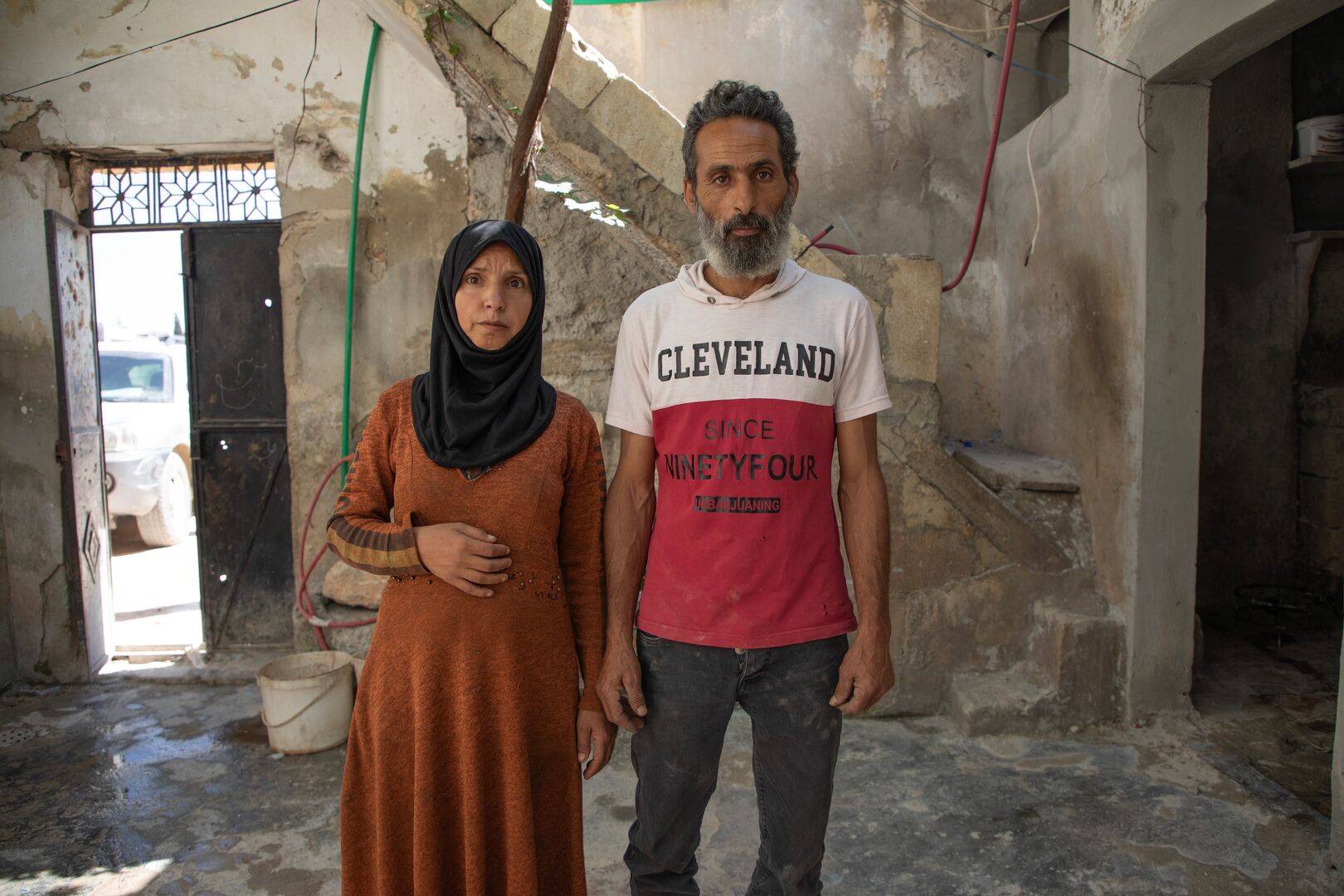 A husband and wife stand in the ruins of their home in Syria