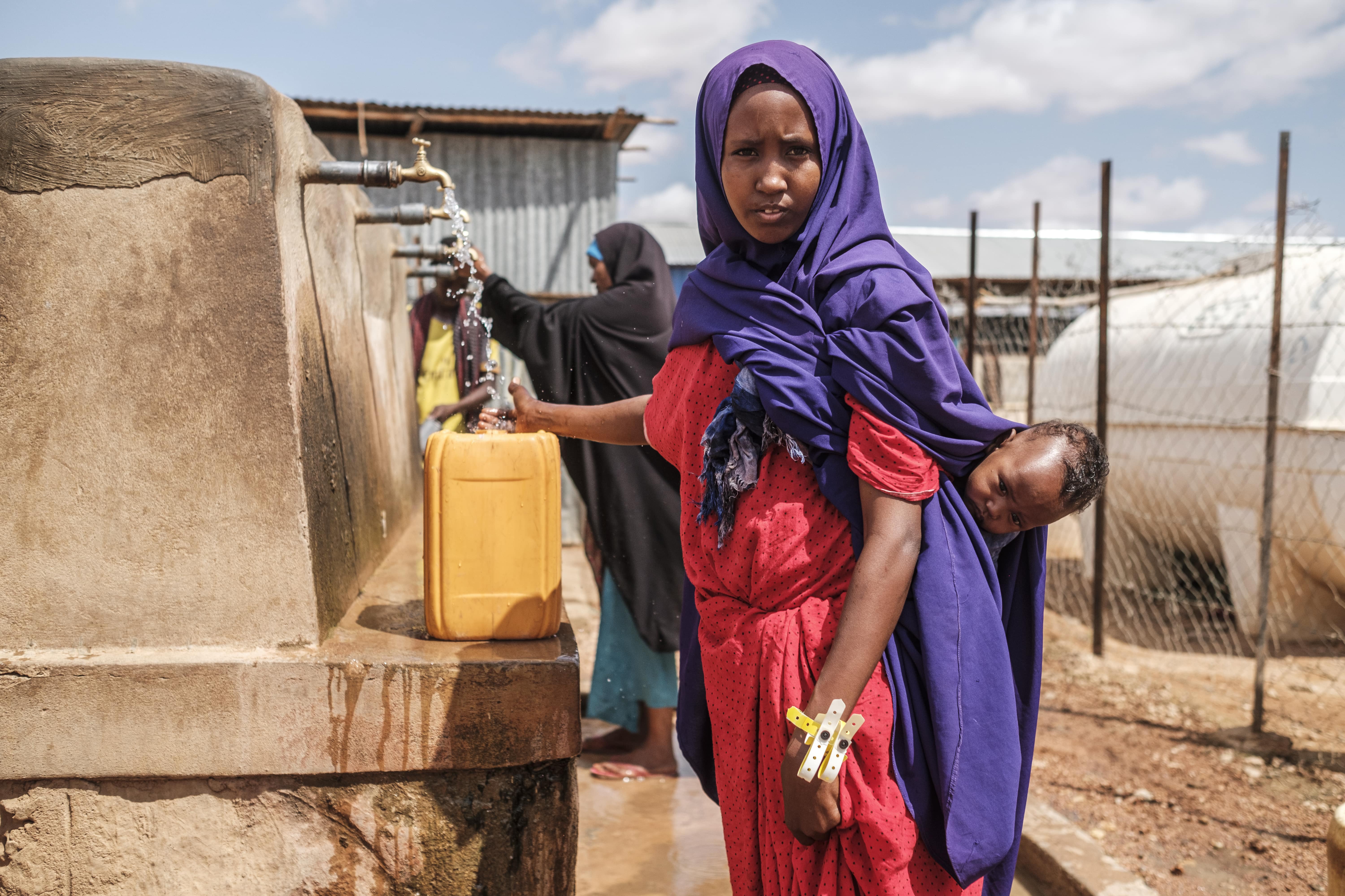 A Somali mother fills a jerry-can with water at UNHCR's reception centre in Dollo Ado, Ethiopia.