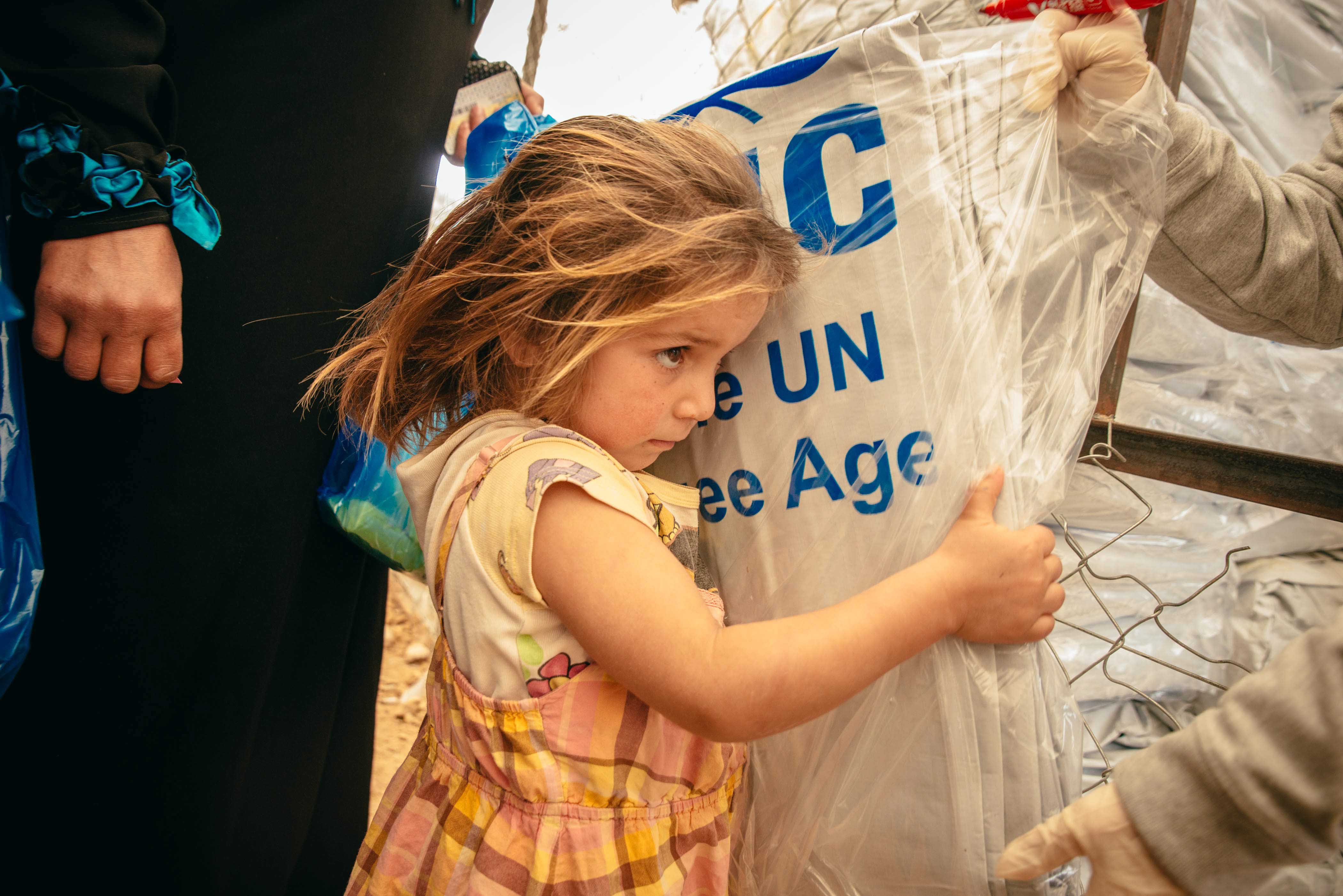 Syrian refugees receive plastic sheets at a distribution center in Jordan’s Zaatari refugee camp.
