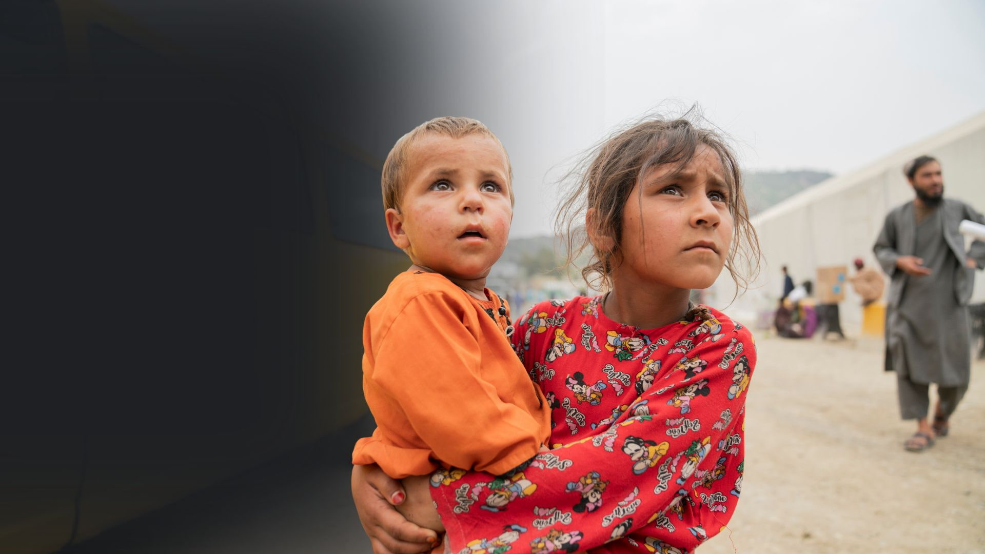 Sheerin Jan, 11, holds her 2-year-old sister Hafsa close as they journey together back to Afghanistan.