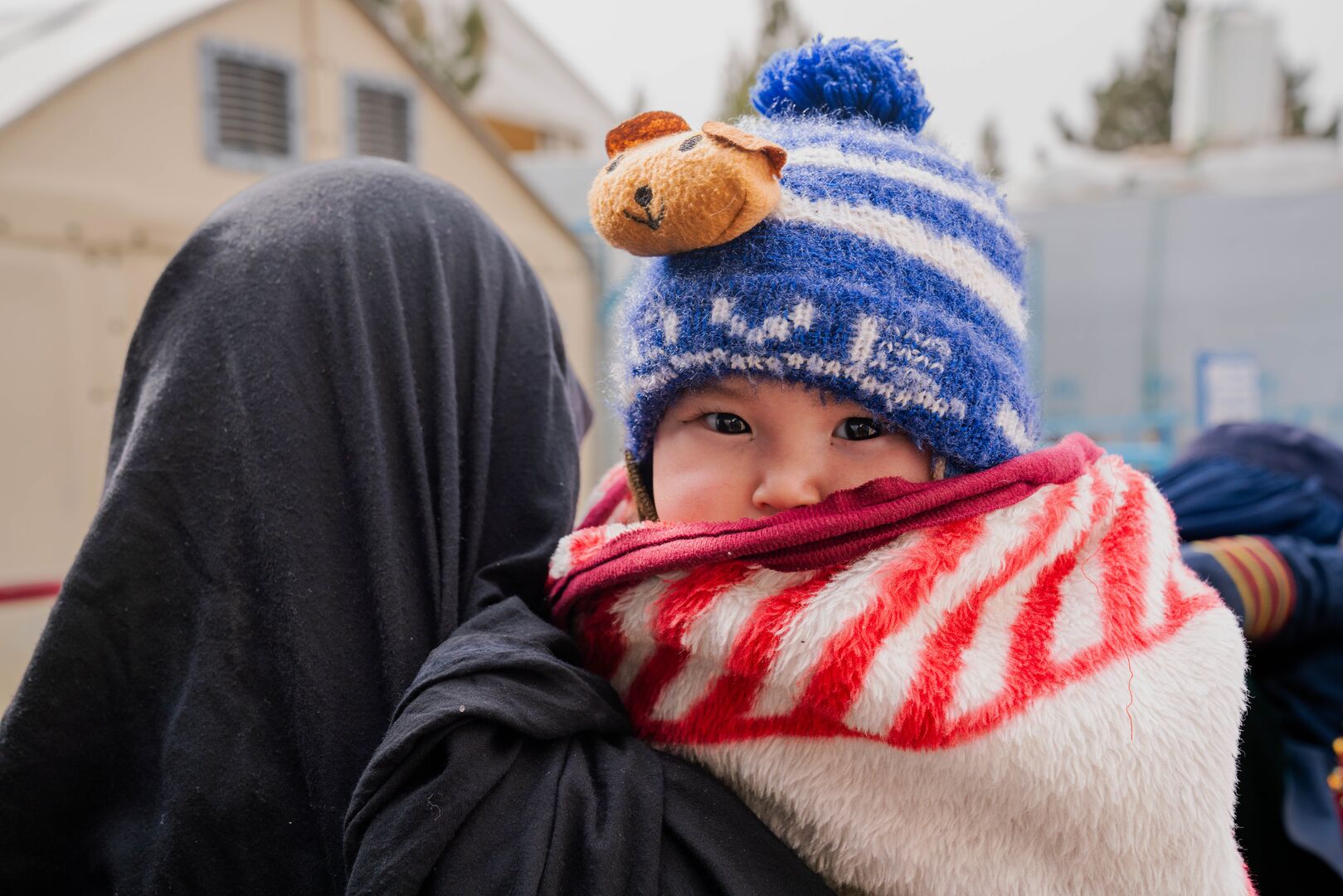 A mother holds her 1 year old son while waiting for aid at a UNHCR distribution centre in Afghanistan