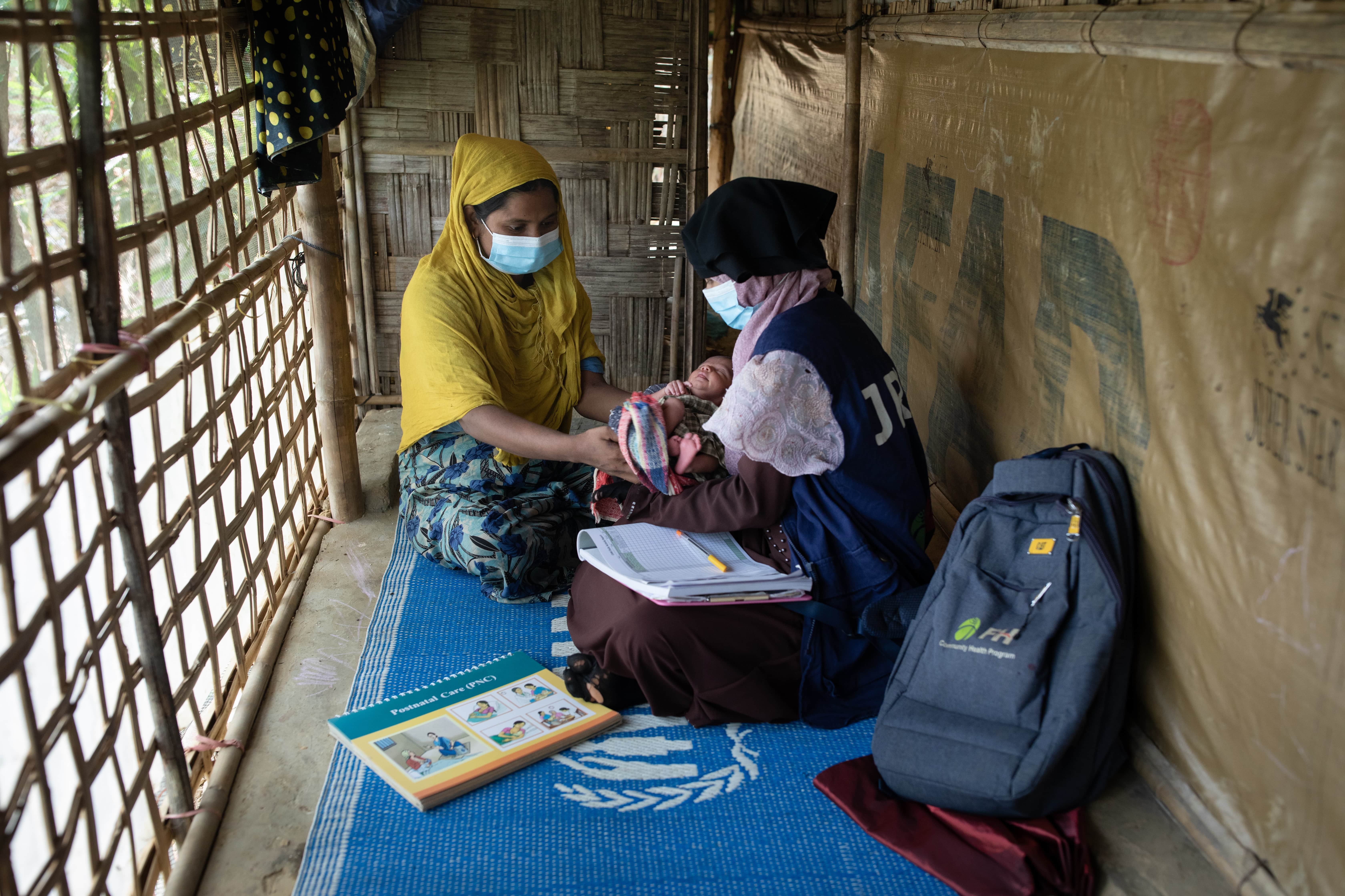  A community health volunteer helps Rohingya mothers with post natal care in Bangladesh.