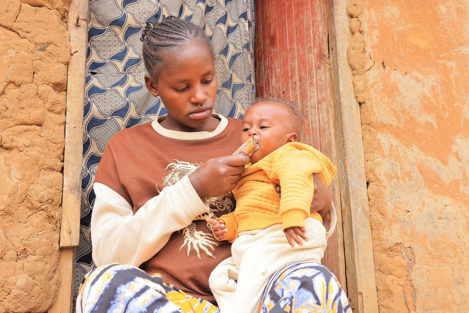 Kabanyana Sarah, a 22-year-old Rwandese refugee from Nyarugugu B in Nakivale Refugee Settlement, feeds her three-month-old son, Prince, with Ready-to-Use Therapeutic Food (RUTF). 