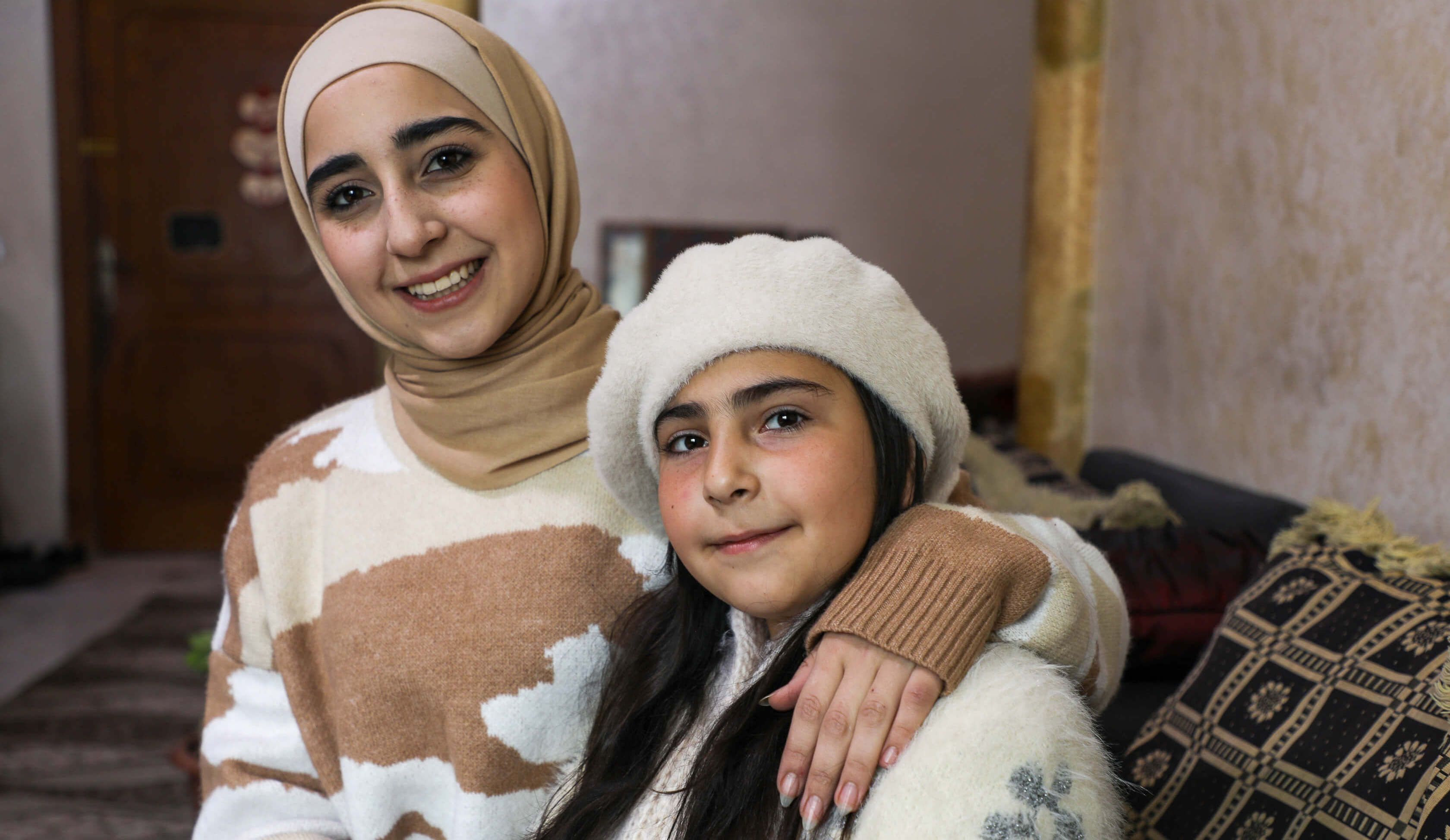 Aya, 20, a Syrian refugee in Jordan is pictured with her younger sister Turkia, 10