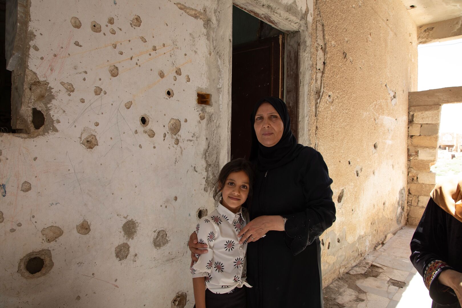 Basmah, 54, stands with her daughter Islam in front of the living room of their damaged house in Al Mansheya in Dar’a Governorate, upon returning back home. 
