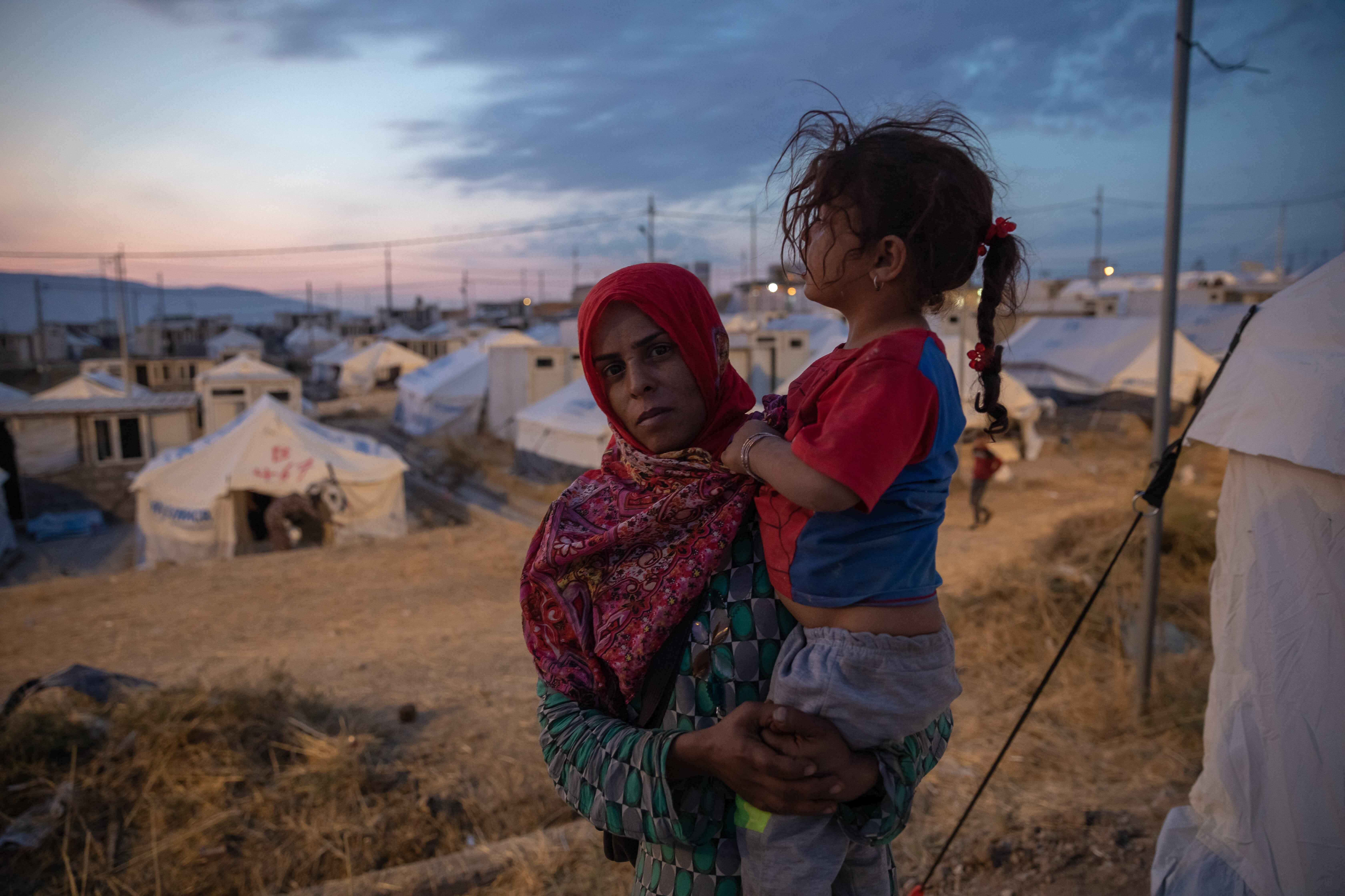 Rojin Ibrahim Davoud, a 28-year-old mother of four, holds one of her children outside a tent in Bardarash camp in Duhok, Iraq.