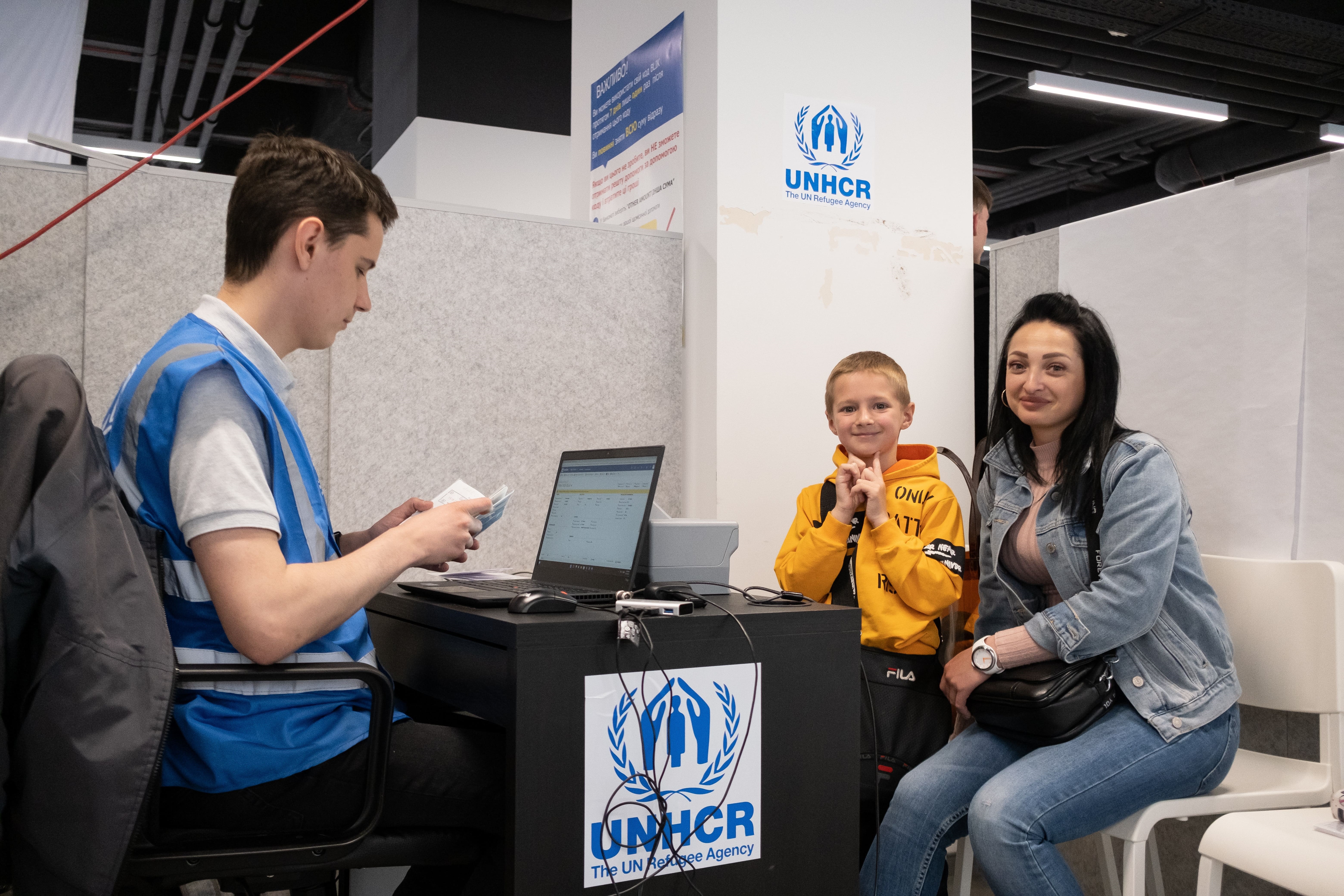 Yulia and her son wait at UNHCR's cash enrolment centre in Poland. They fled their home in Ukraine in March. 